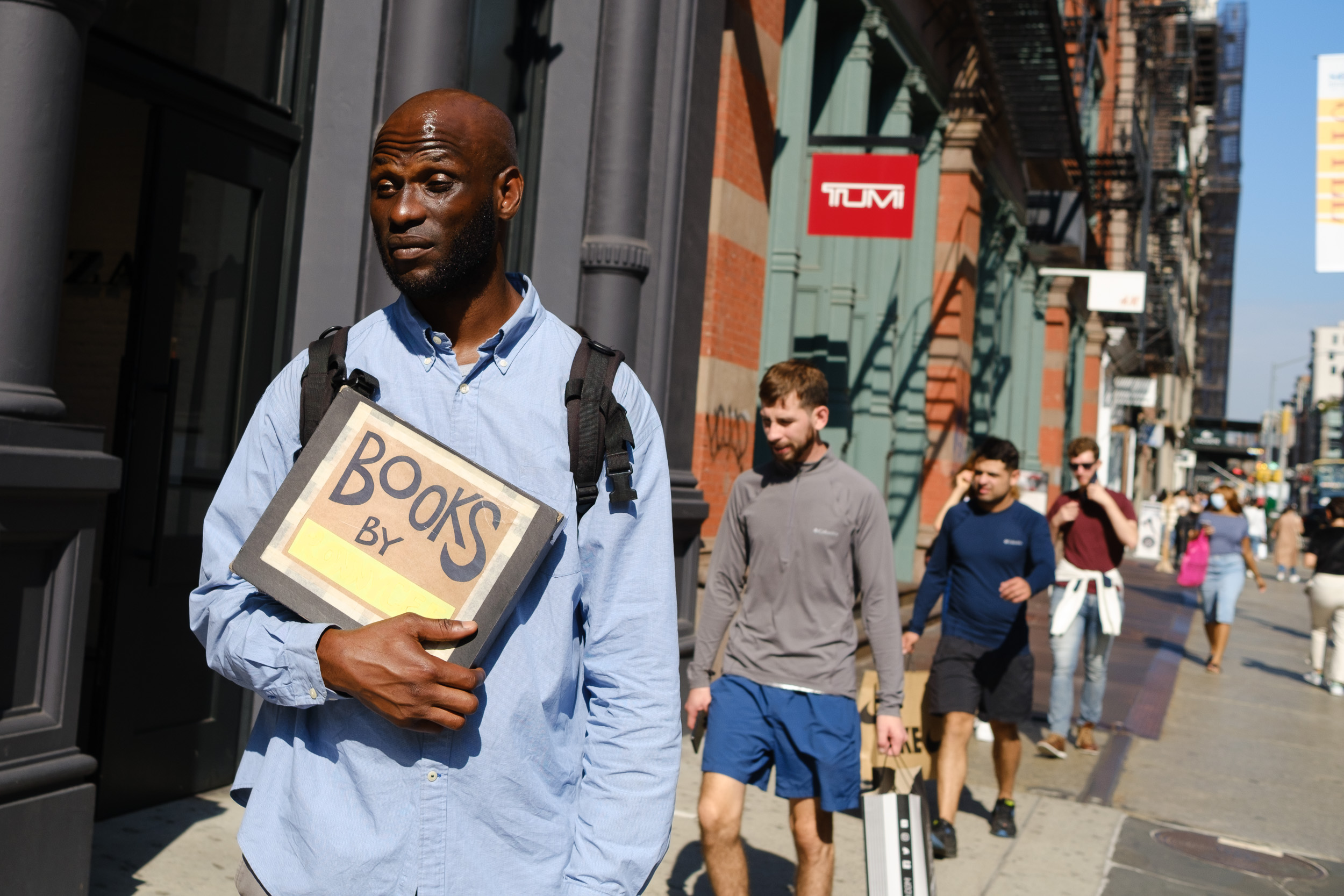 Man holding books by sign  in soho nyc